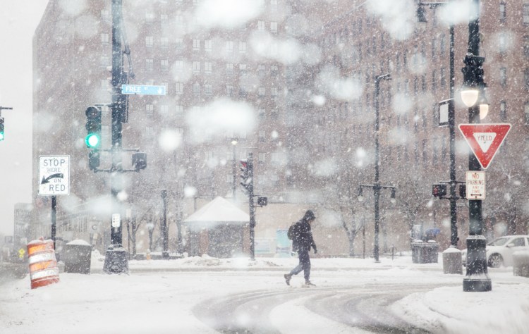 A pedestrian crosses High Street in heavy snow on Wednesday morning in Portland.