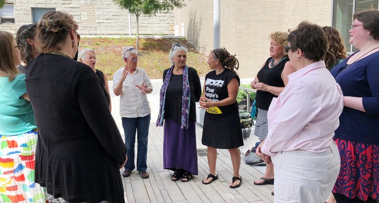 Defendants charged in May with criminal trespass at the Blaine House confer with each other and one of their attorneys after a hearing in August at the Capital Judicial Center.