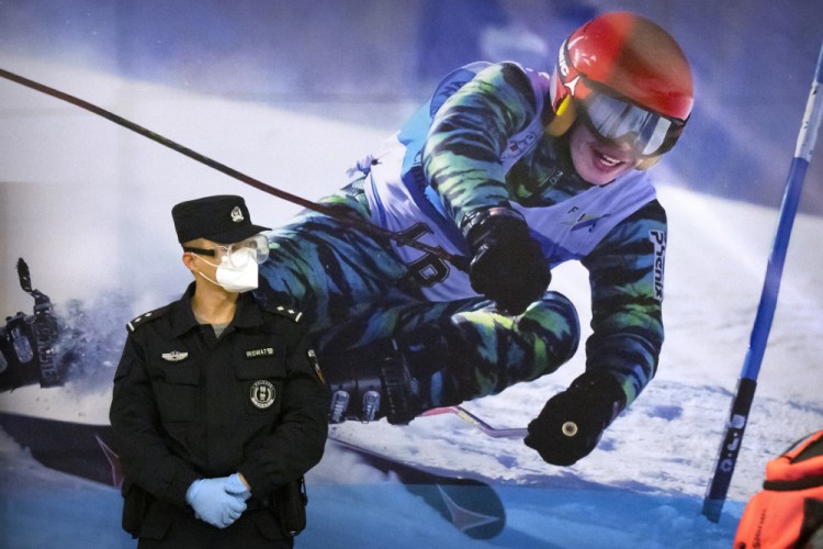 A police officer  stands near a poster of a skier on the wall at a train station in Zhangjiakou in northern China's Hebei Province, in November.