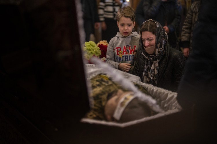 A woman and a boy react next to the body of Ukrainian Army captain Anton Sydorov, 35, killed in eastern Ukraine, during his funeral, in Kyiv, Ukraine, Tuesday, Feb. 22, 2022. Western leaders said Tuesday that Russian troops have moved into rebel-held areas in eastern Ukraine after President Vladimir Putin's recognized their independence — but some indicated it was not yet the long-feared full-fledged invasion as confusion reigned in the region. 