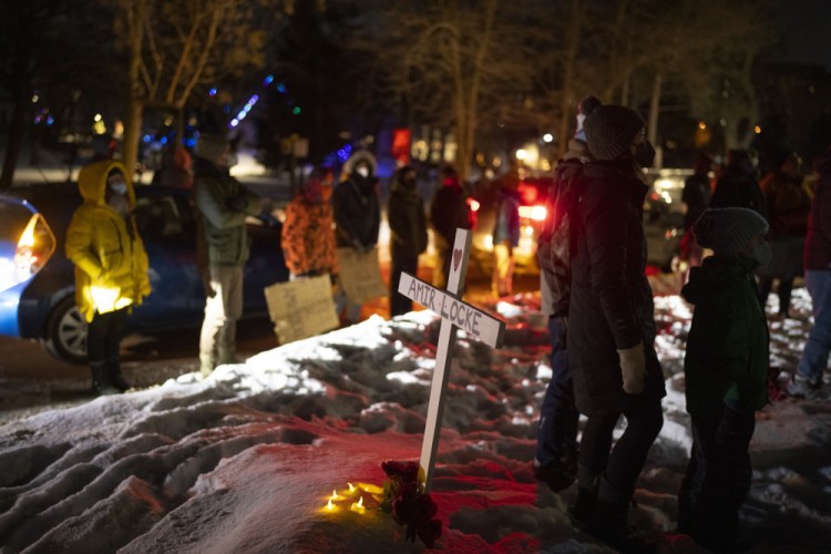 People stand by a cross planted in the boulevard in Minneapolis on Sunday night.

